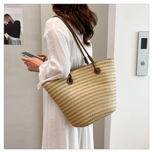 Détails de la texture du sac cabas en paille tressée avec rayures et anses en cuir