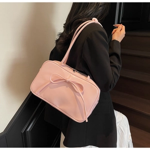 Pink Boston bag with bow accent worn by a model in a minimalist indoor setting