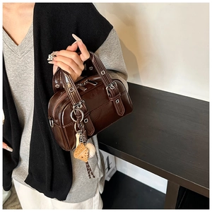 Detail of dark brown glossy Boston bag with silver hardware and baseball leather charm