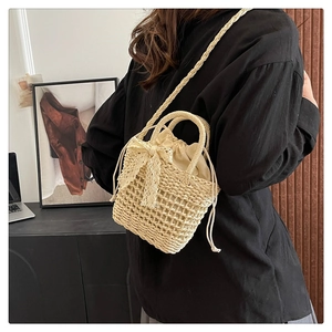 Detailed close-up of woven beige straw bucket bag with delicate lace bow and drawstring