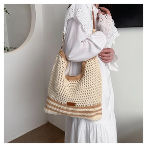 Detailed close-up of handmade hollow woven tote bag with brown leather logo and wooden bead strap