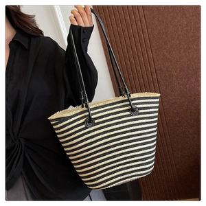 Détail du sac cabas en paille tressée avec rayures noires et blanches et franges