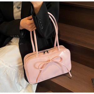 Pink Boston bag with bow decoration and double handles worn as a shoulder bag