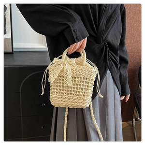 Detail of beige woven straw bucket bag with drawstring liner and lace bow decoration