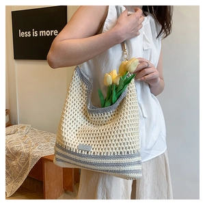 Detailed knit texture of crochet shoulder bag with contrasting stripes and gold metal hook
