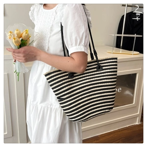 Détail du sac cabas tissé à rayures noires et blanches avec bretelles en cuir sur mannequin
