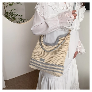 Close-up of minimalist crochet tote bag with contrast stripes and decorative wooden beads