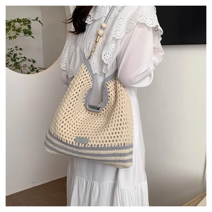 Detail of hand-woven shoulder bag with contrasting blue stripes and wooden beads
