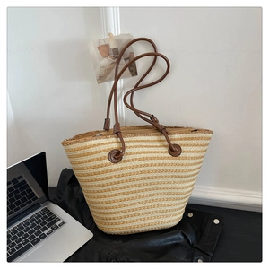 Détail du sac cabas tissé rayé avec anses en cuir marron et renforts circulaires