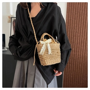 Detail of woven straw bucket bag featuring a large lace bow and drawstring closure