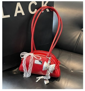 Détail d'un sac à main rouge vintage avec nœud en dentelle et breloques en métal
