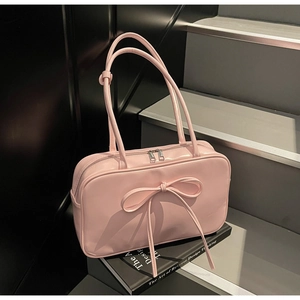 Detail of pink bow Boston bag with silver zippers placed on a black book for decor