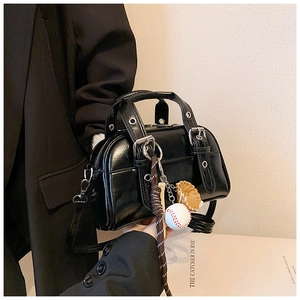 Close-up of black glossy Boston bag featuring silver hardware and a baseball charm detail