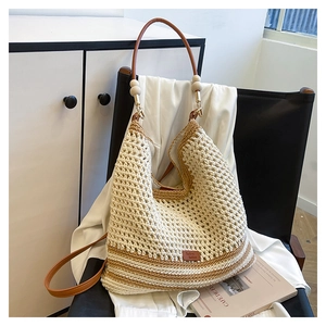 Close-up of beige woven shoulder bag with brown leather strap and wood bead accents