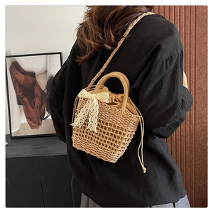 Detail of woven straw beach bag featuring lace bow decoration and drawstring liner