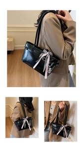 Détail du sac à bandoulière noir brillant avec ruban rose et breloque en cœur