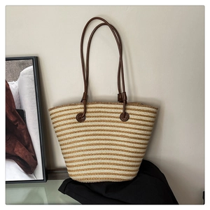 Détail du sac fourre-tout tissé à rayures avec poignées en cuir et texture en paille