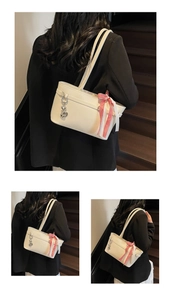 Détail du sac cabas en cuir blanc avec ruban à carreaux rouges et pendentif coeur