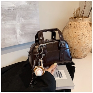 Detail of dark brown glossy Boston bag with silver hardware and baseball bag charm