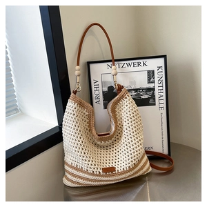 Detail of woven tote bag featuring contrast stripes, wooden beads and leather strap