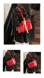 Détail du sac à épaule en cuir verni rouge avec un nœud à carreaux et des breloques
