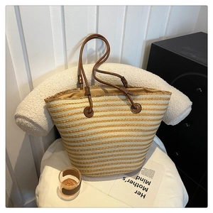 Détail du sac cabas en paille tressée avec rayures et poignées en cuir marron