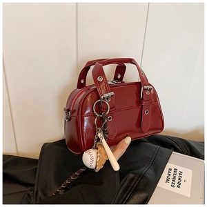 Close-up of red patent leather Boston bag on black jacket with baseball charms