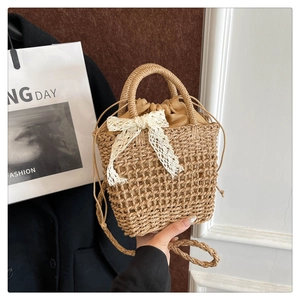 Detail of woven straw handbag featuring a white lace bow and drawstring inner bag