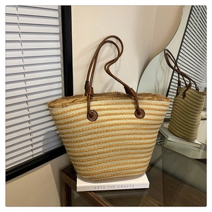 Détail du sac cabas en paille rayé avec poignées en cuir marron et bords à franges