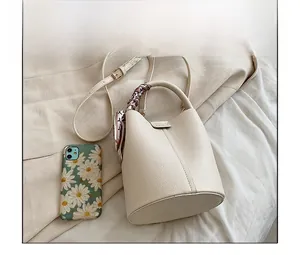 Detail of off-white bucket bag with lychee texture leather and floral scarf handle