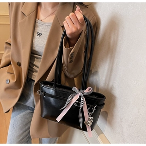 Détail du sac cabas en similicuir noir avec ruban nœud élégant et pendentif en cœur