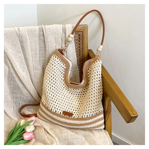 Detail of hollow woven tote bag with brown leather straps and decorative wooden beads