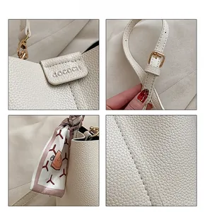 Detailed macro view of cream pebbled leather bucket bag with GOCDCH logo and silk scarf