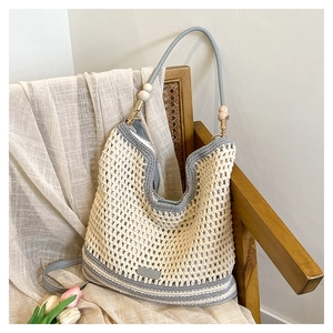 Detail view of woven mesh tote bag featuring decorative wooden beads and leather patch