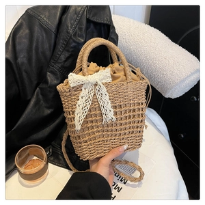 Detail of straw woven handbag featuring lace bow and brown drawstring inner bag