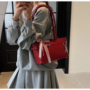 Détail du sac en cuir rouge brillant avec pendentif coeur et ruban à carreaux rouge