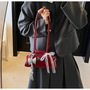Détail du sac Boston en cuir rouge foncé avec nœud argenté et ruban de dentelle blanc