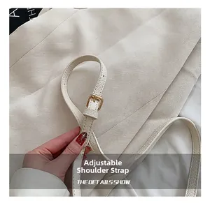 Detail of adjustable cream leather shoulder strap with golden buckle for the bucket bag