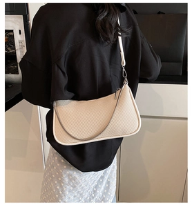 Detail view of beige crossbody underarm bag with silver chain strap and textured finish
