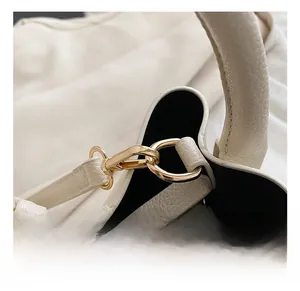Detailed close-up of premium golden hardware on white litchi pattern leather handbag