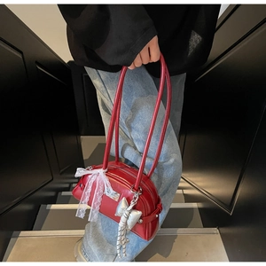 Détail du sac en cuir verni rouge avec dentelle blanche et pendentif nœud argenté