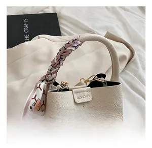 Detailed close-up of cream leather bucket bag handle wrapped in a silk scarf