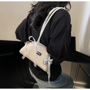 Détail du sac bandoulière en cuir PU crème avec nœud en dentelle et breloque argent