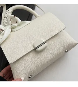 Detail of creamy white litchi pattern leather bag with floral bear scarf and metal feet