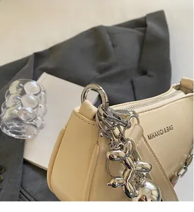 Détail du sac à bandoulière en cuir mat beige avec breloque chien ballon argentée et zip