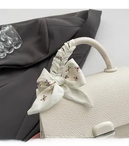 Close-up of cream leather handbag handle with silk scarf and teddy bear pattern