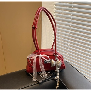 Détail du sac rouge en cuir verni avec nœud en dentelle blanche et pendentif papillon