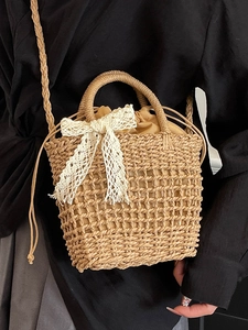 Woven straw handbag with white lace bow and drawstring inner lining for beach holidays