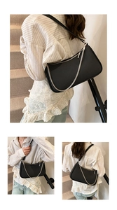 Detail view of black baguette bag featuring textured surface and elegant silver chain strap