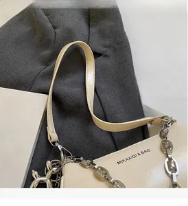 Gros plan du sac à main crème en cuir PU avec chaîne argentée et breloque chien ballon